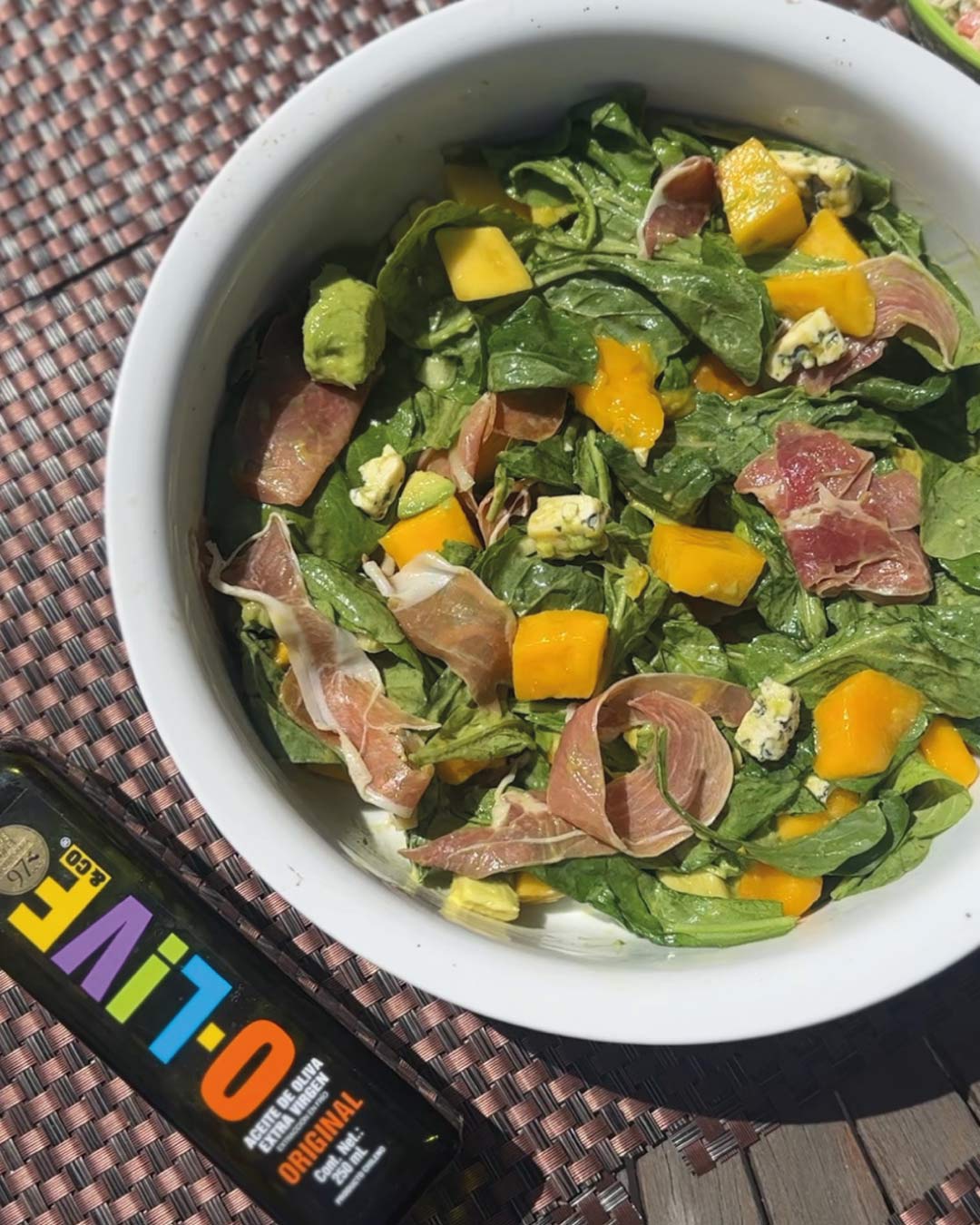 Bowl de ensalada de espinacas con mango, palta, queso azul y jamón serrano.