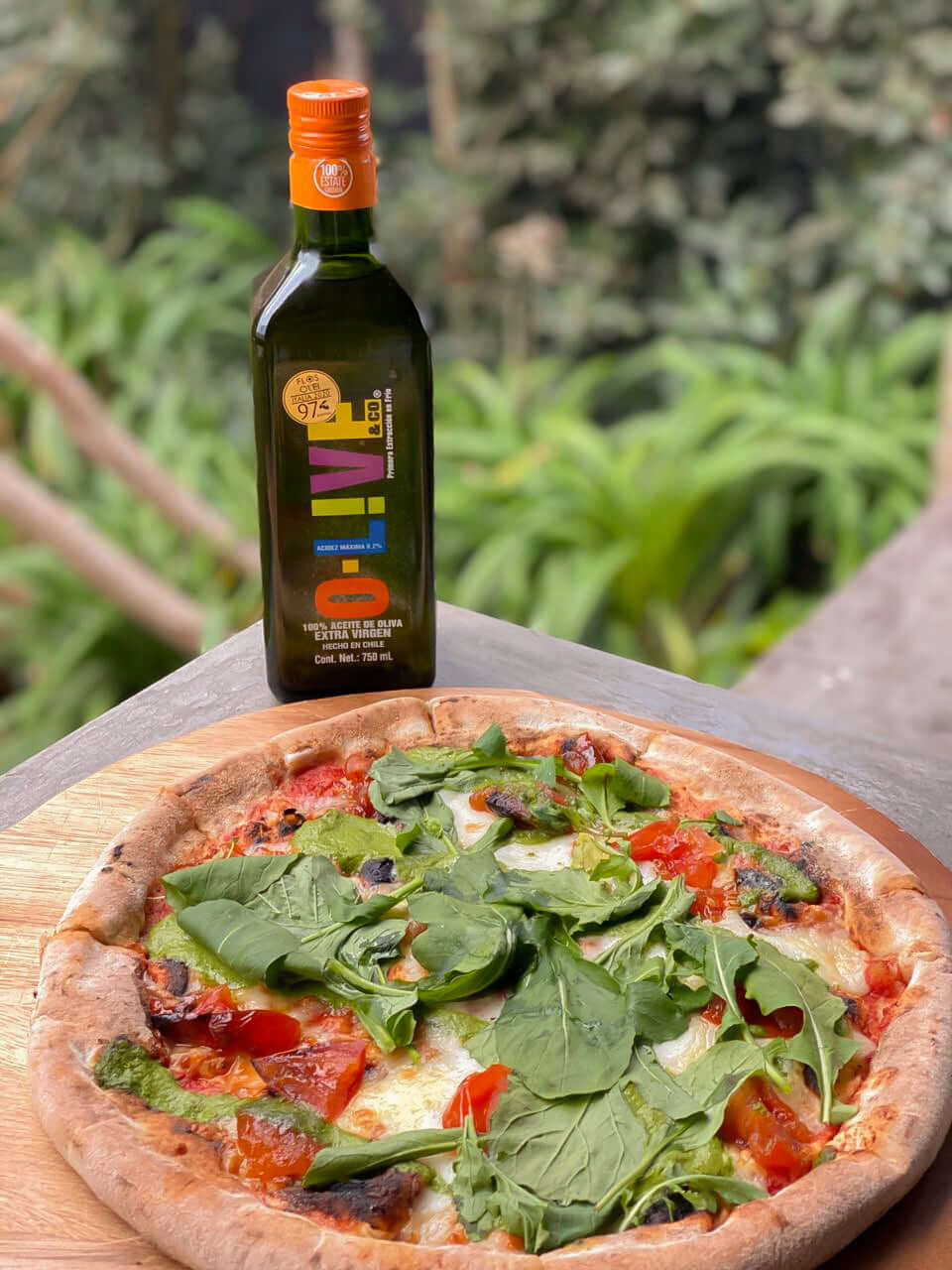 Pizza a la piedra con una botella de aceite de oliva O-Live & Co