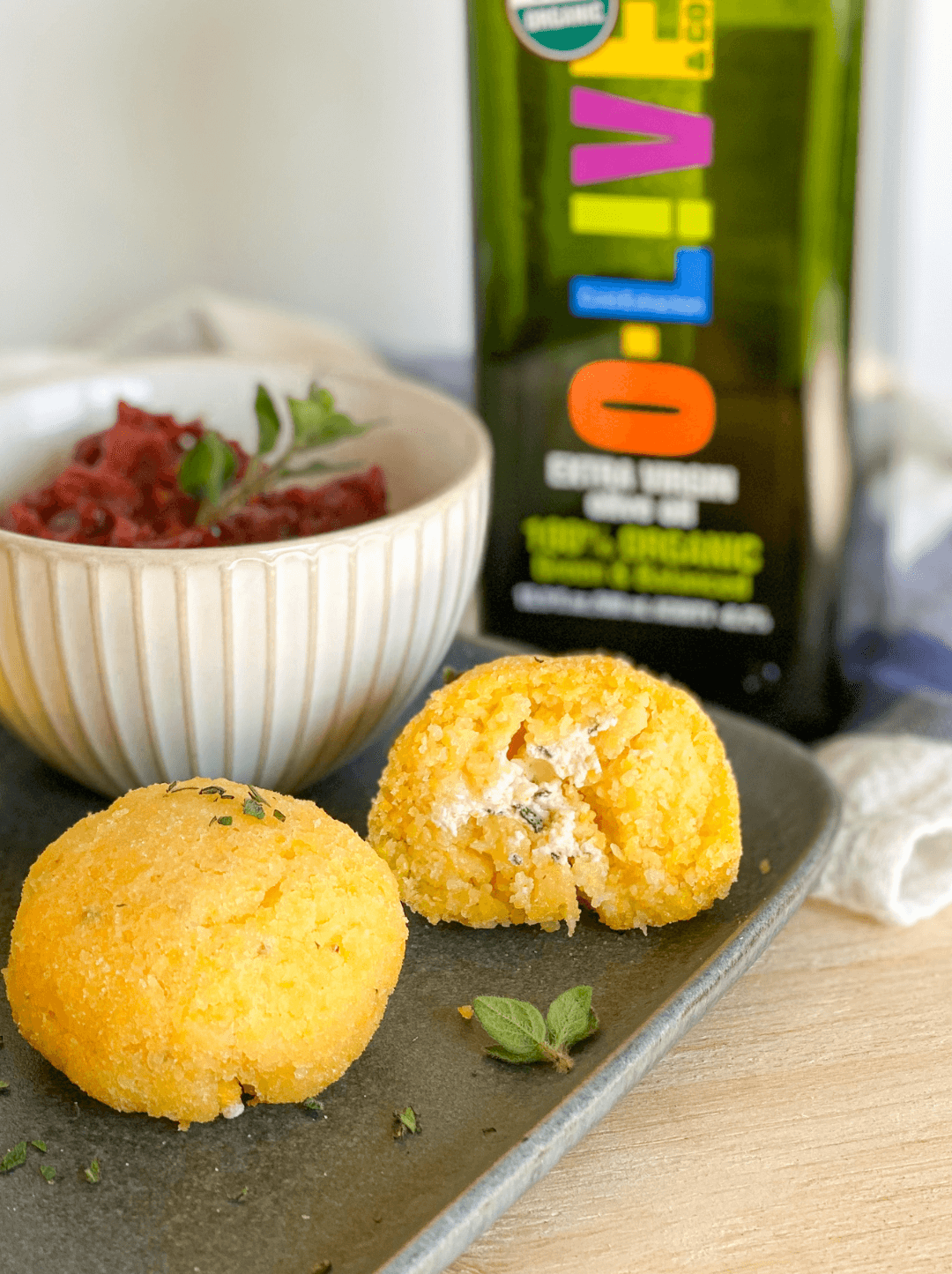 Dos bocaditos de ricotta hechos en Air Fryer junto a una botella de aceite de oliva O-Live & Co.