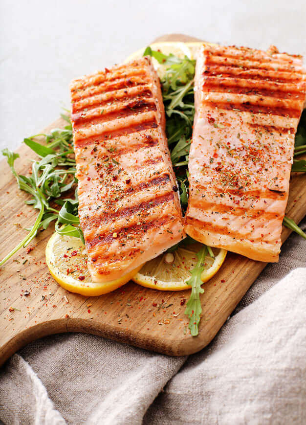 Receta preparada de Salmón al Horno, servido en una tabla de madera de cocina