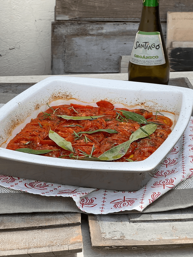 Bandeja con salsa de tomate y hojas de laurel junto a una botella de aceite de oliva Santiago Premium.