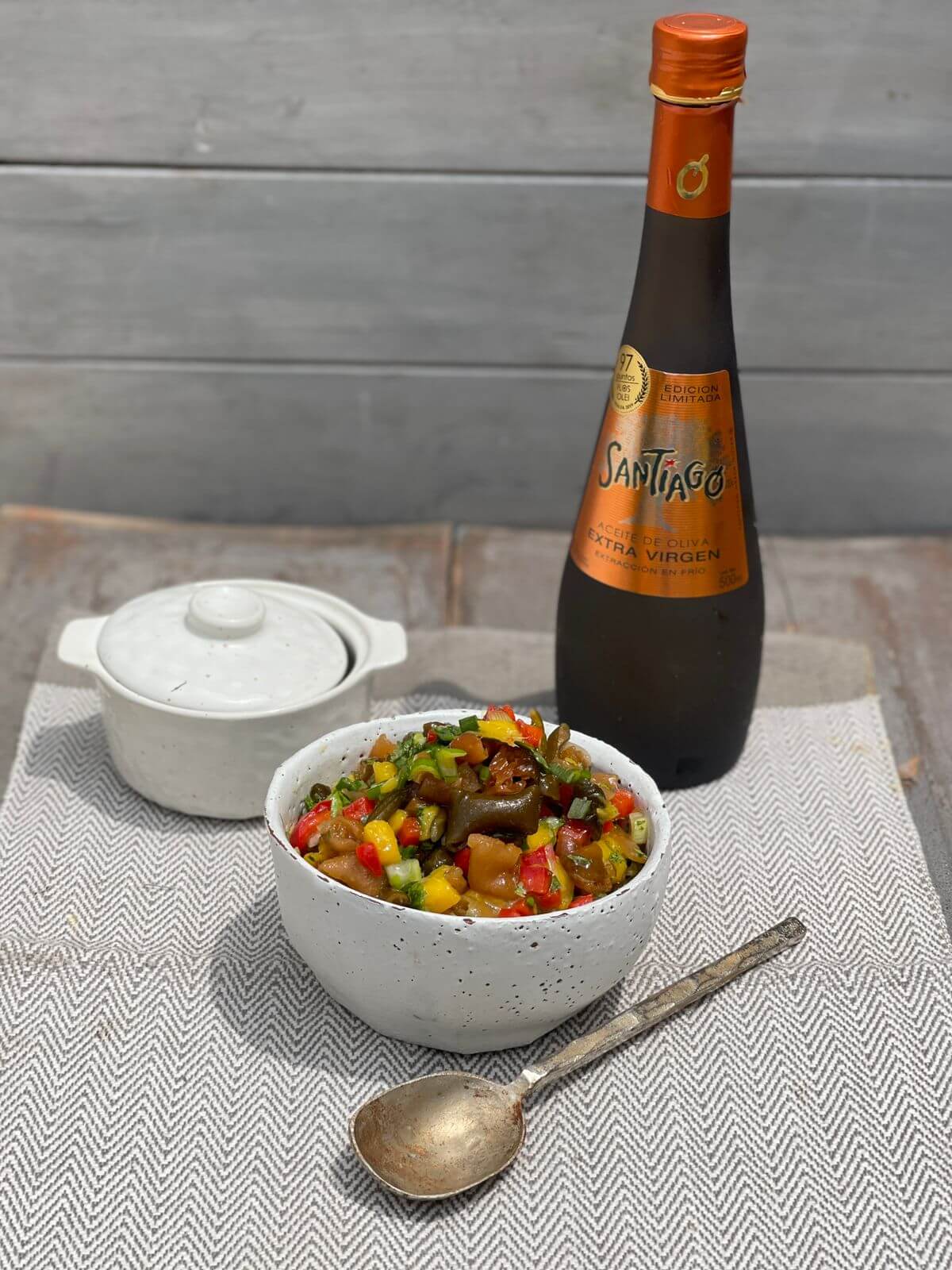 Recipiente con Pebre de cochayuyos junto a una botella de 500ml de aceite de oliva Santiago Premium.