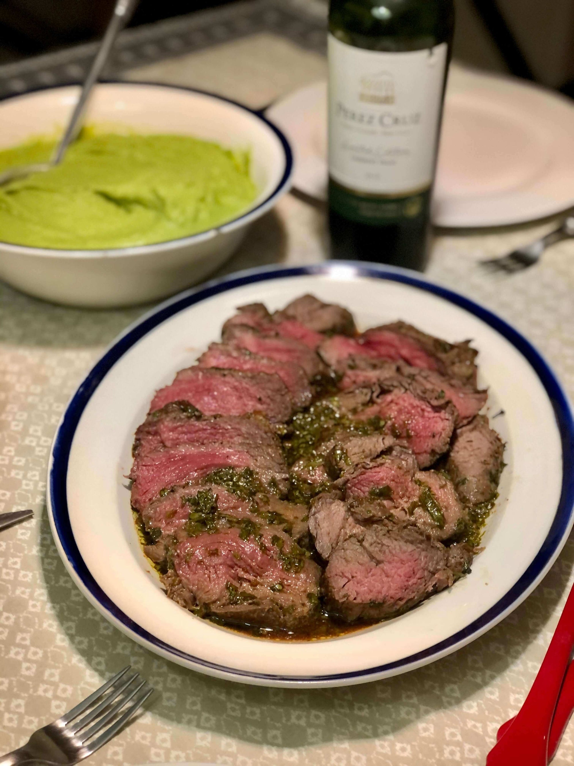 Plato de filete al cilantro servido en un plato blanco y acompañado de una botella de aceite de oliva O-Live & Co