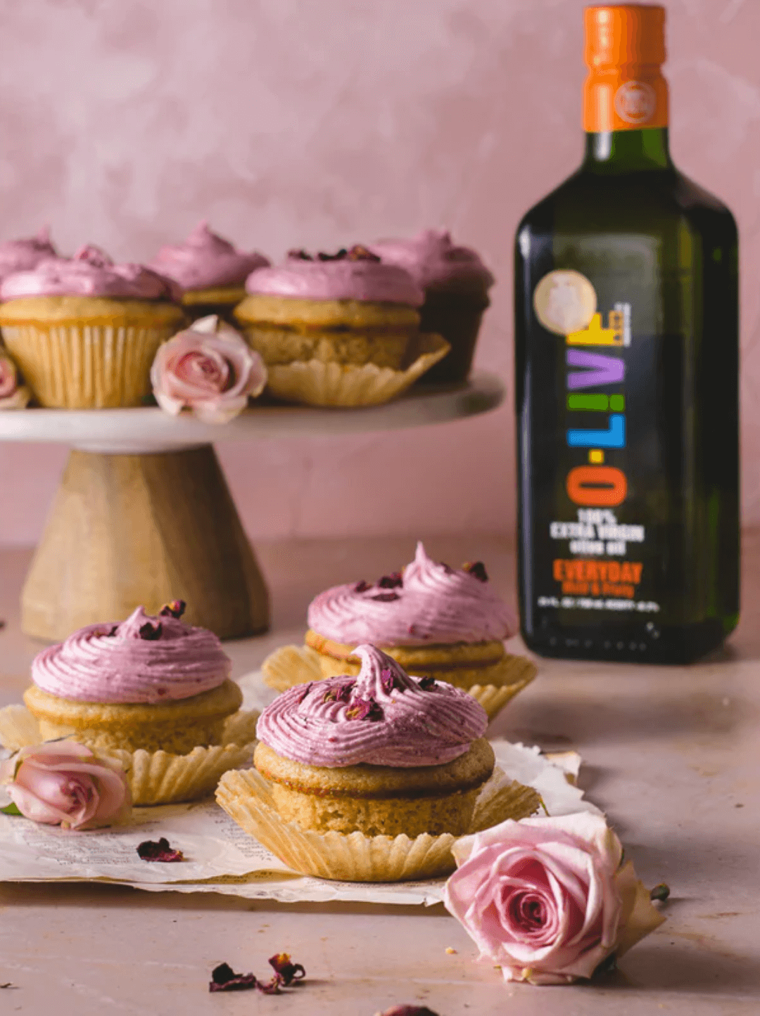 Cupcakes de frambuesa y rosas junto a una botella de 500ml de aceite de oliva O-Live & Co.