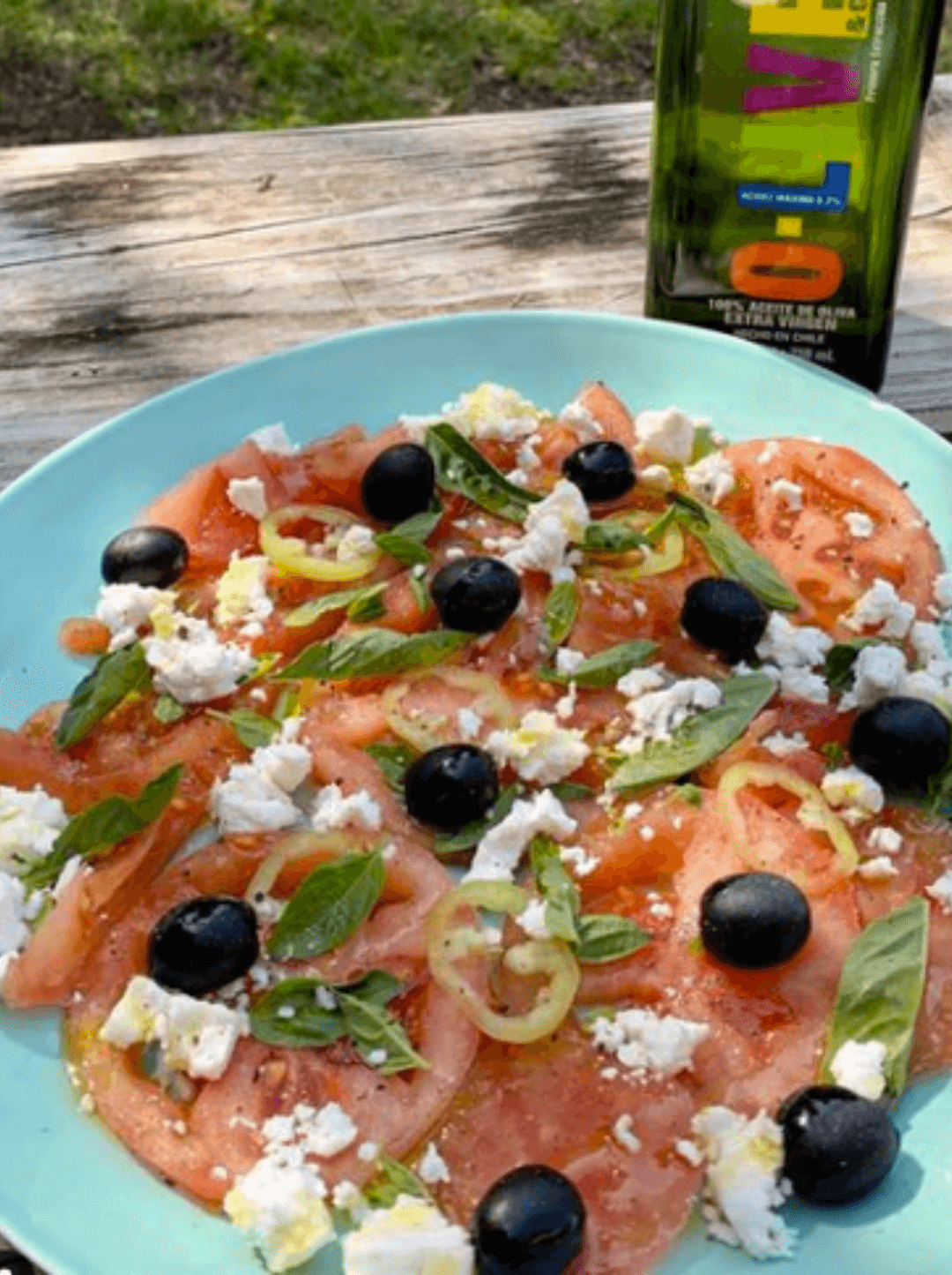 Ensalada de Tomates y Feta junto a una botella de aceite O-Live & Co.