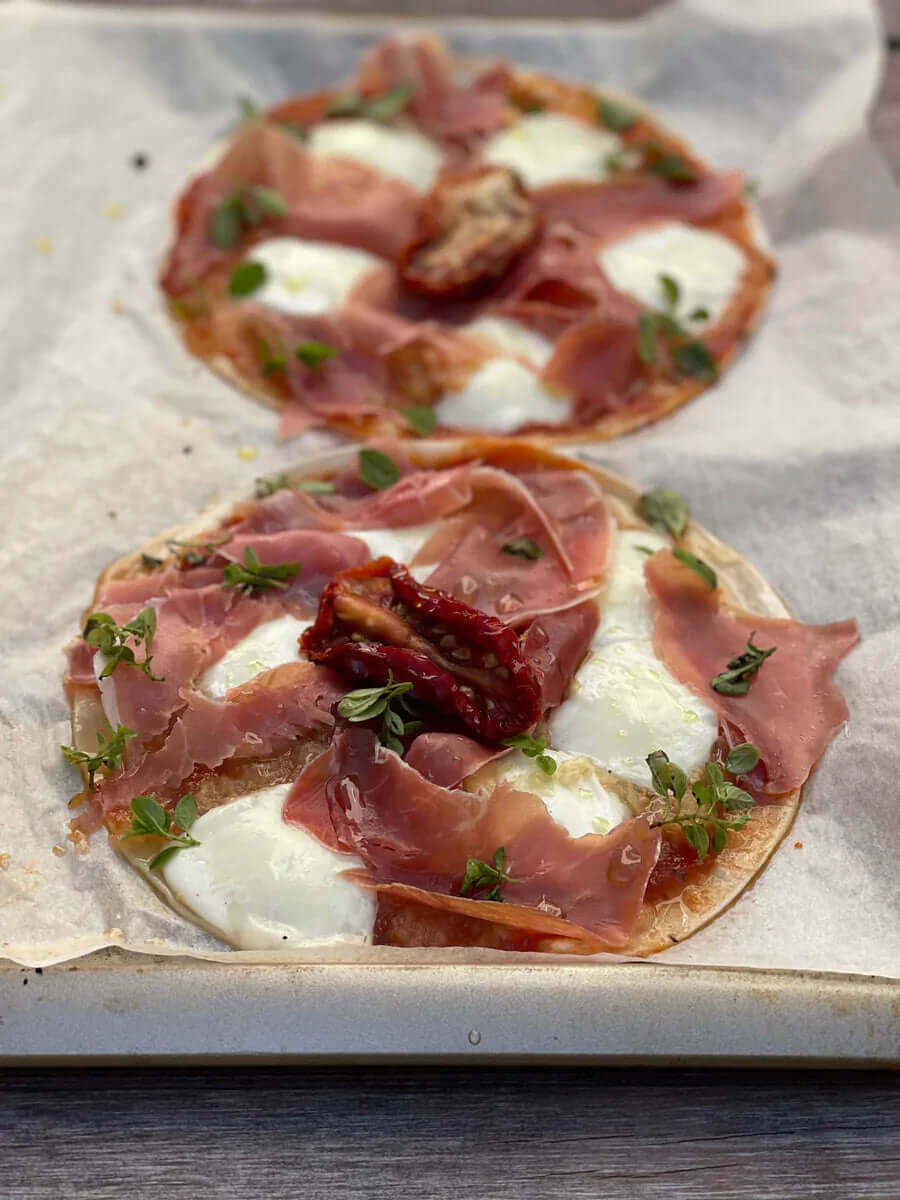 Dos mini pizzas caseras con queso y jamón crudo
