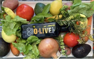 Botella de aceto O-Live&Co entre frutas y verduras 